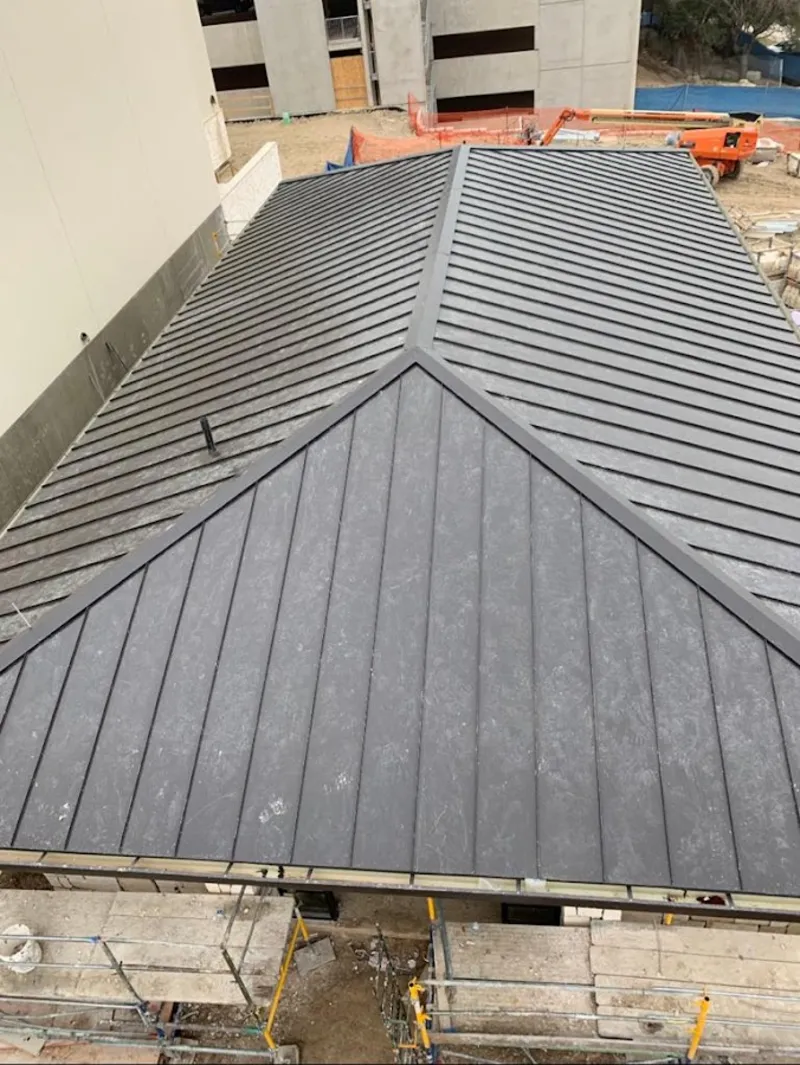 Commercial metal roof construction with crane equipment in Roxbury